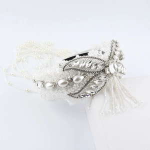 Detailed macro view of white lace bridal headband with crystal beads and pearl tassels