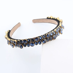 Detail view of gold-tone headband with deep blue crystals and velvet lining
