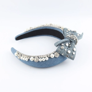 Detail view of denim headband with sparkling rhinestones, pearls, and bow decoration