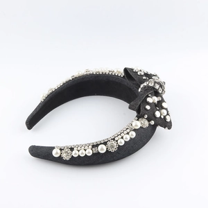 Detailed close-up of a black fabric headband featuring faux pearls and rhinestones