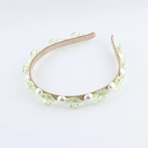 Dettaglio dei fiori trasparenti verde chiaro e delle perle bianche sulla fascia per capelli