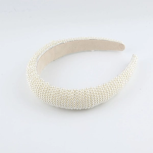 Detailed close-up of handmade wide headband with dense white pearls and soft beige lining