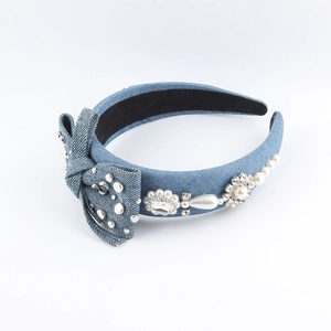Detailed view of blue denim headband with bow, faux pearls and rhinestone flowers