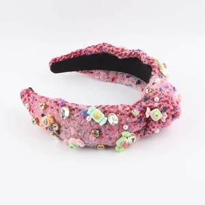 Détail d'un serre-tête en tweed rose orné de breloques bonbons et de perles