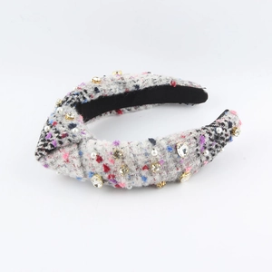 Nahaufnahme von grauem Tweed-Knotenstirnband mit glitzernden Strasssteinen und Perlen