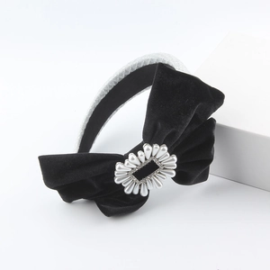 Detail of black velvet bow headband with faux pearls and rhinestones on a silver frame