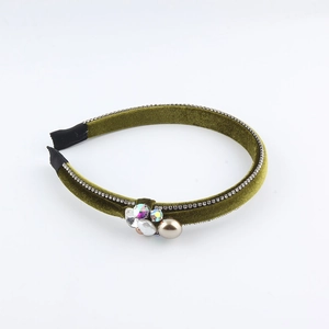 Detail of green velvet headband with side-mounted faux pearl and sparkling rhinestones