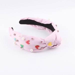 Dettaglio del cerchietto rosa con nodo, cuori colorati, perle e cristalli