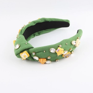 Dettaglio del cerchietto in velluto verde con ciondoli a cartone animato e strass scintillanti