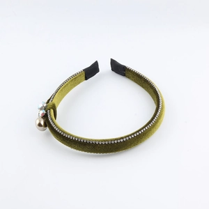 Macro shot of dark green velvet headband with rhinestones and a gold metal ball charm