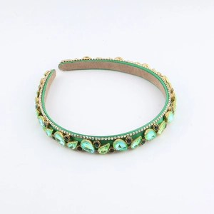 Detail of luxury green satin headband with emerald gemstones and white rhinestones
