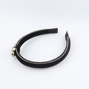 Detailed close-up of velvet headband with rhinestone inlay and champagne pearl charm