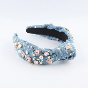 Detail eines hellblauen Denim-Knoten-Haarreifens mit rosa Kristallen, Perlen und Fransen