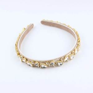 Close-up of golden headband featuring sparkling rhinestones and beige velvet lining
