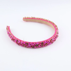 Détail d'un serre-tête magenta de luxe orné de cristaux et d'une base dorée