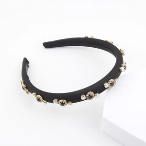 Detail showing black satin padded headband with gold floral rhinestones and AB crystal studs