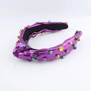 Détail d'un serre-tête noué violet métallisé orné de perles et strass colorés