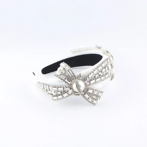 Detail of luxury wide headband with crystal bows and white pearls on white fabric
