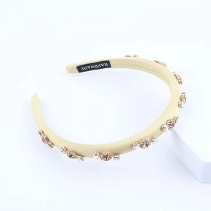 Detail of handmade beige satin headband featuring sparkling brown and iridescent rhinestones