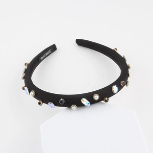 Détail du serre-tête en éponge noire fait main avec strass colorés et perles blanches