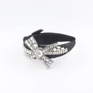 Detail of black pleated headband with oversized rhinestone bow and white pearls