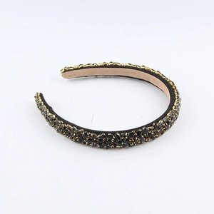 Détail de strass noirs sur base dorée avec doublure en velours doux sur le serre-tête