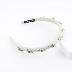 Detail showing handmade velvet headband with green rhinestones and crystal emerald gems