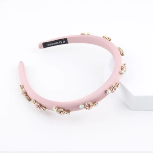 Close-up of pink satin padded headband with rhinestone flowers and handmade label