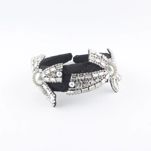 Close-up of black fabric headband with faux pearls and crystals in vintage floral patterns
