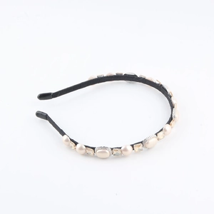 Detail view of French style headband featuring cream pearls and yellow square gems on black fabric