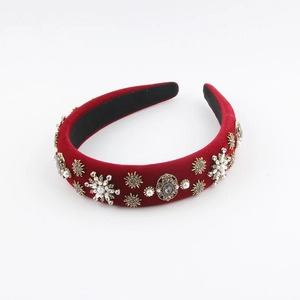 Détail d'un serre-tête en velours rouge avec perles, strass et flocons dorés
