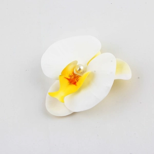 Vista macro di un fermaglio orchidea bianca con centro giallo e dettaglio di perla finta