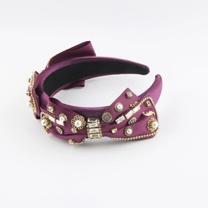 Detailed macro view of purple satin headband with crystals, pearls and gold floral accents
