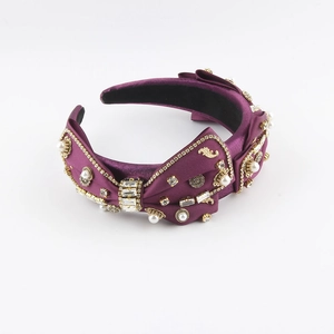 Detailed macro shot of purple satin headband with crystal bow and pearl accents