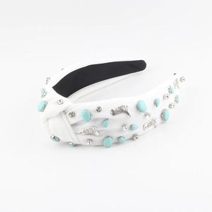 Detailed macro view of white fabric knotted headband with blue stones and silver accents
