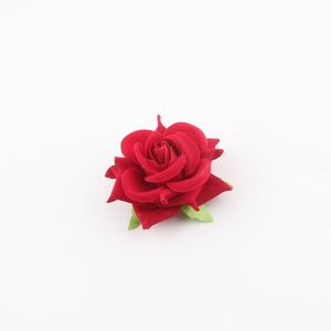Dettaglio di una rosa finta in tessuto rosso intenso con petali e foglie verdi