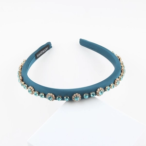 Elegant peacock blue handmade headband with light blue rhinestones on a white stand