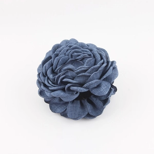 Dettaglio macro della molletta a rosa in denim blu con petali stratificati e texture fine