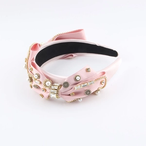 Pink satin headband with rhinestones, pearls and bow detail for a stylish look