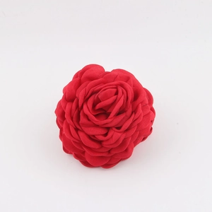 Dettaglio ravvicinato di un fermaglio a rosa in raso rosso con petali in tessuto multistrato