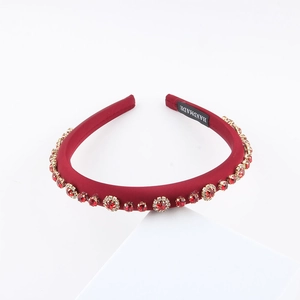 Detail of handmade red rhinestone headband with gold claw settings and satin fabric