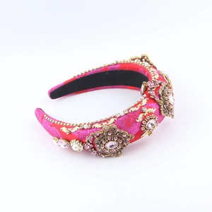 Detailansicht eines rosaroten Satin-Haarreifens mit goldenen Metallblumen und Strasssteinen