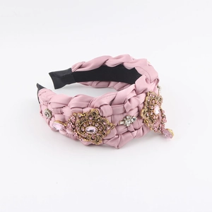 Detail eines rosa gewebten Satin-Haarreifens mit goldenen Blumen und rosa Kristallen