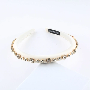 Detail of a handmade cream padded satin headband with sparkling rhinestones in gold claw settings