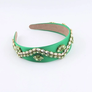 Detail of green satin headband featuring intricate emerald rhinestones and crystal clusters