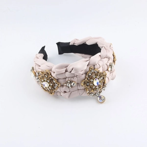 Detail eines rosa geflochtenen Satin-Stirnbands mit goldenen Blumen und Kristallherz