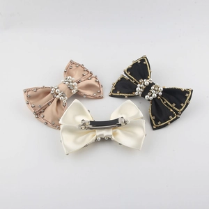 Three bow hair clips with pearls and rhinestones in black, beige, and champagne colors