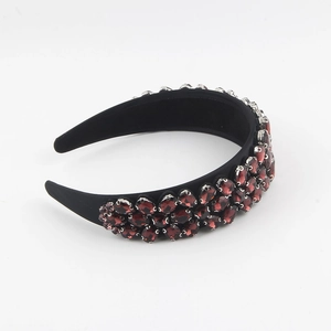 Détail d'un serre-tête baroque fait main avec strass rouge foncé sur tissu velours