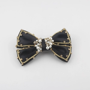 Close-up of black satin bow hair clip with gold trim, pearls and rhinestones