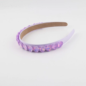 Dettaglio di un cerchietto viola chiaro con cristalli a cuore e fodera interna opaca